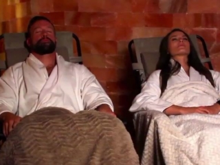 Purlux Spa And Salon. Man In Woman Who Are Both In White Robes Laying Back And Relaxing In Lounge Chairs.