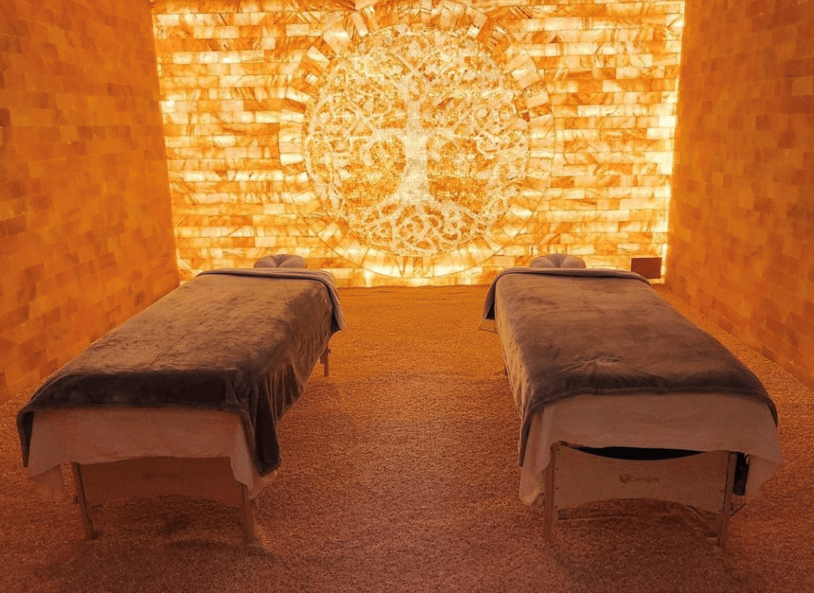 A Salt Room With Two Massage Tables In Front Of A Himalayan Salt Wall.