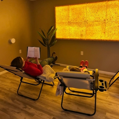 Two People Sitting In Reclining Chairs In The Salt Room At Reset Spa &Amp; Massage Salt Therapy In Saint Marys, Arkansas With Himalayan Salt Panels On The Wall.