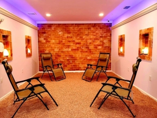 Salt Aer Studios. Four Lounge Chairs In Each Corner Of Salt Room Facing Each Other. The Back Wall Is A Brick-Styled Salt Wall And The Side Walls Have Openings To Hold Glowing Salt Rocks.