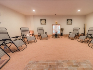 Seven Reclining Chairs In A Room With Salt-Covered Floors And A Buddha Statue In The Far End Of The Room In Front Of An Led Backlit Salt Panel