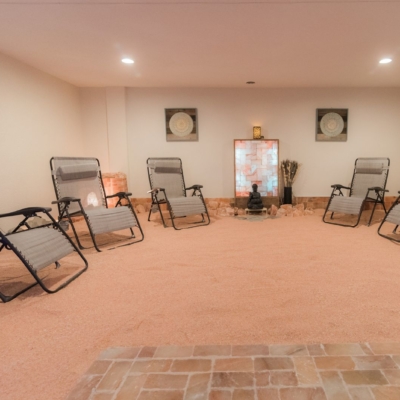 Seven Reclining Chairs In A Room With Salt-Covered Floors And A Buddha Statue In The Far End Of The Room In Front Of An Led Backlit Salt Panel