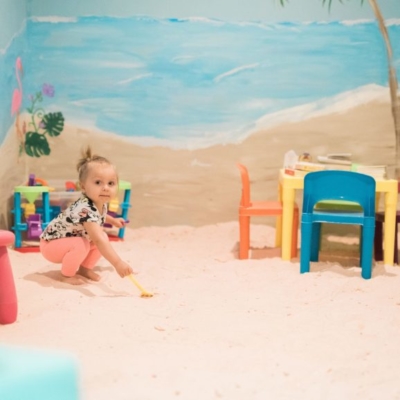 Halotherapy room with a young girl on a salt-covered floor with a play table and toys at the Serenity Salt Spa LLC in Forest Hill, Maryland