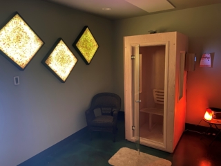 A Salt Booth With The Door Open In A Room With 3 Salt Panels Hanging From The Wall At Sol Health Yoga In Puyallup, Washington.