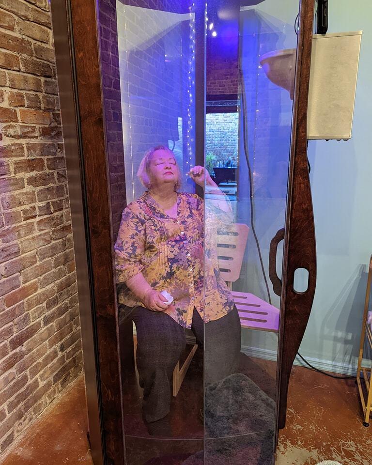 A woman sitting in a SALT Booth for a salt therapy session at Solace Wellness Studio in Boston, Georgia.