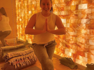 Sweet Be Wellness And Skin Clinic. Woman Doing A Tree Pose Yoga Position In Front Of Salt Tiled Wall In Spa Room.
