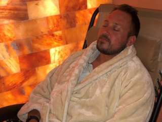 Sweet Be Wellness And Skin Clinic. Man In White Robe Laying Back In Reclining Chair With Eyes Closed In Salt Room