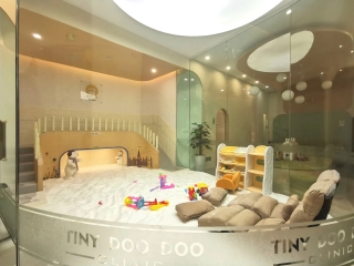 A glass surrounded children's salt room with two tan cushion chairs, a salt-covered floor, and toys at the TSR Bear in Taiyuan, Shanxi, China