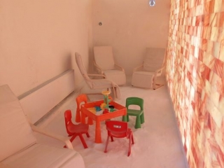 The Salt Box. Narrow Salt Room With Children'S Chairs And Table In The Middle. In The Back Part Of The Room Are Regular Chairs As Well.