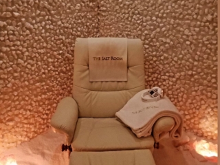 The Salt Room. Recliner In Corner Of Salt Room. Headphones On Top Of Towels Lay On The Chair And A Cloth Is Draped Over The Back Of The Chair That Reads &Quot;The Salt Room.&Quot;