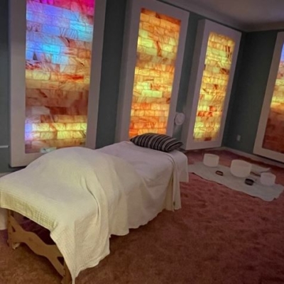 Willoway Spa &Amp; Wellness Center. Colorful Salt Room With A Massage Bed In The Middle. Salt Tiles Are A Mixture Of Pink, Blue, Yellow And White.