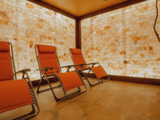 The Healing Den Of Salem. Three, Orange Lounge Chairs Lined Up Next To Each Other Surrounded By Salt Tiled Walls.