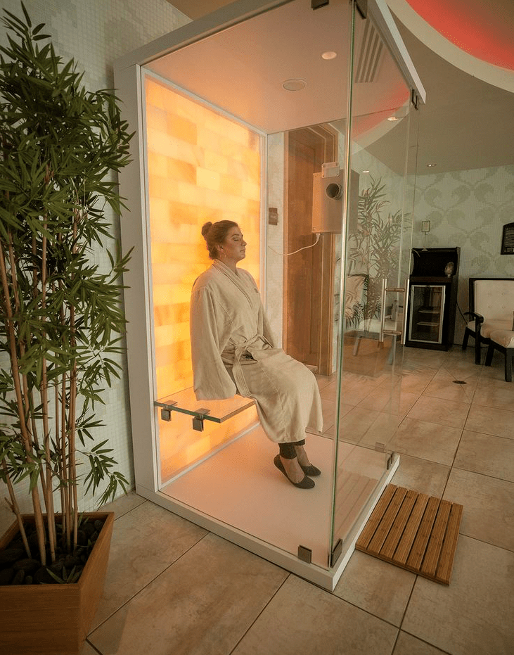 Agua Caliente Resort Casino Spa. Woman in white robe sits inside of glass salt chamber.