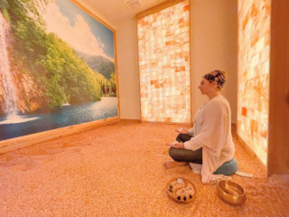 Wellcome Om Integral Healing &Amp; Education Center. Woman Meditates While Sitting On Top Of Salt Floor Facing A Mural Of A Waterfall.