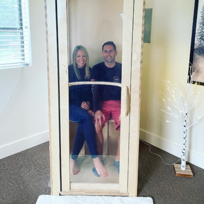 Woman and man sitting in a wooden and glass salt booth smiling at the The Restoration Place Clinic Orlando, Florida.