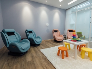 Four chairs, two light blue and two light pink, in a blue room with a white area rug and a children's play table.