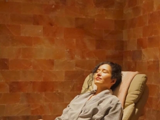Woman Relaxing On A Chair In Front On A Himalayan Salt Panel Wall At The Art Of Balance Wellness Spa - Baltimore, Maryland.