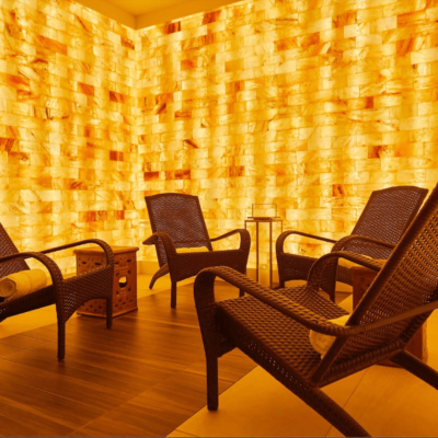 Four lounge chairs with white towels rolled up in a LED backlit Himalayan salt panel room in Bergamos Retreat - Friendswood, Texas