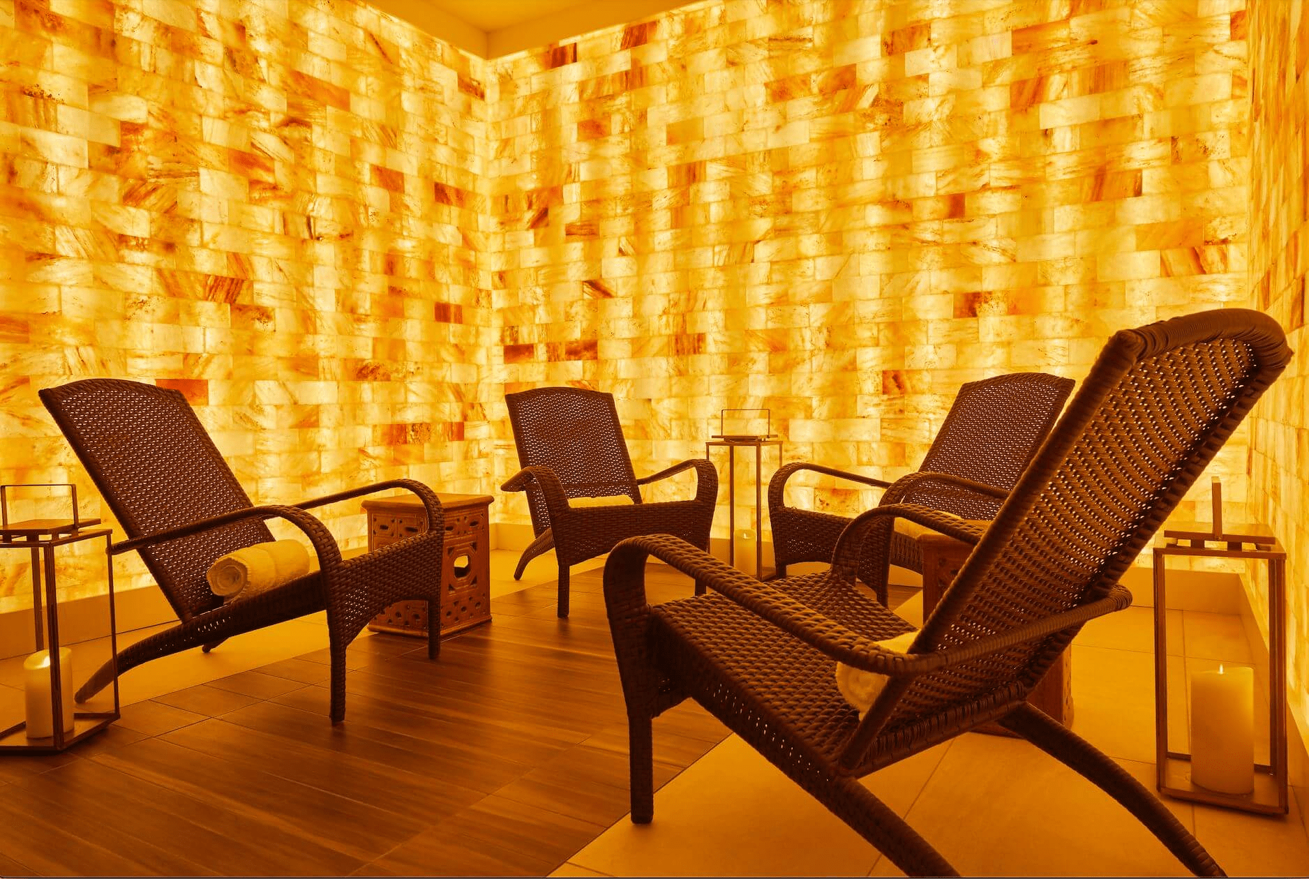Four lounge chairs with white towels rolled up in a LED backlit Himalayan salt panel room in Bergamos Retreat - Friendswood, Texas