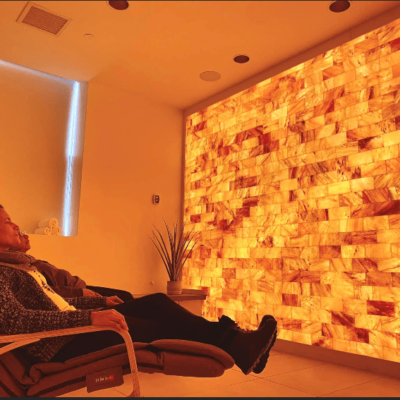 Two Woman Reclined In Chairs Facing An Orange Backlit Salt Paneled Wall At The Beth Abraham Center For Rehabilitation And Nursing In Bronx, New York