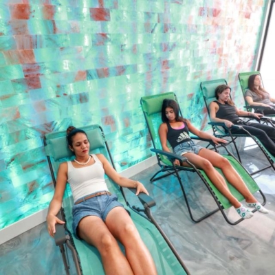 4 women relaxing in lounge chairs in front of a green colored salt brick wall at Boca Cryo in Boca Raton, Florida