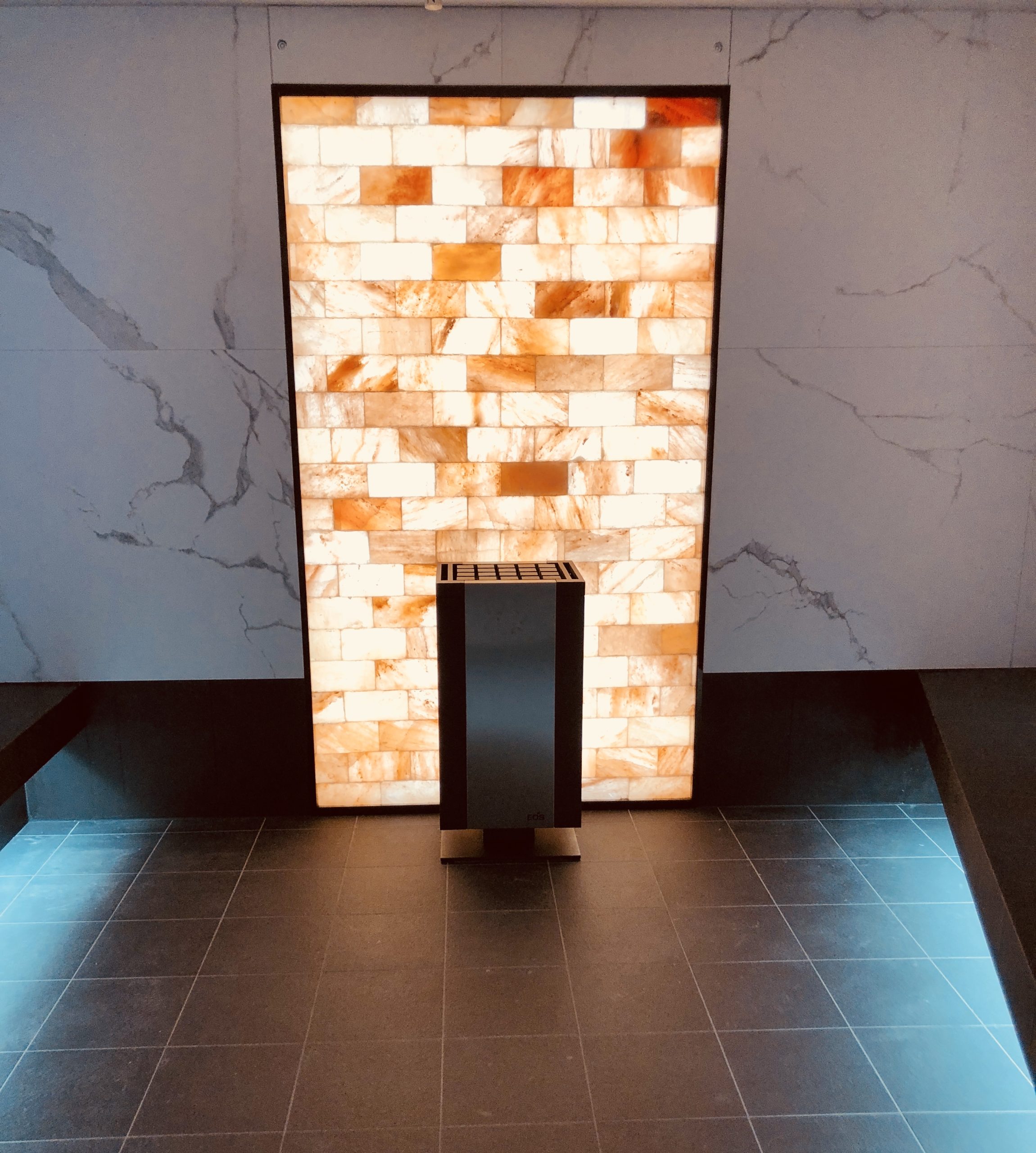 An Orange Back Lit Himalayan Salt Stone Panel On A Granite Wall And A Grey Squared Tile Floor On The Celebrityedge.