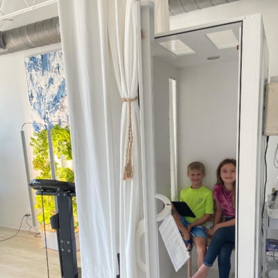Two smiling children sit inside a Salt Booth at Cryo You in Fort Lauderdale, Florida
