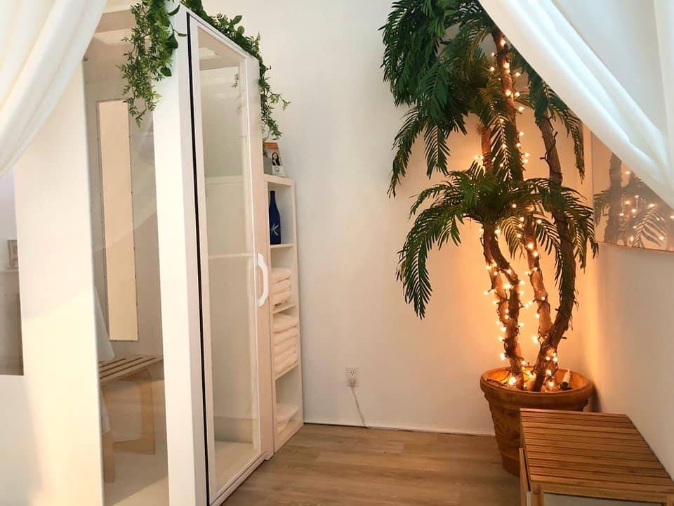 Side view of a salt booth and a potted tree inside Cryo You in Fort Lauderdale, Florida