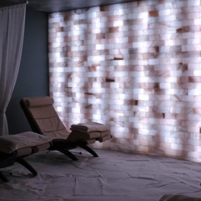 A White Salt-Covered Floor With Two Reclining Chairs In Front A White Backlit Salt Paneled Wall At The Dolce Organic Salon.