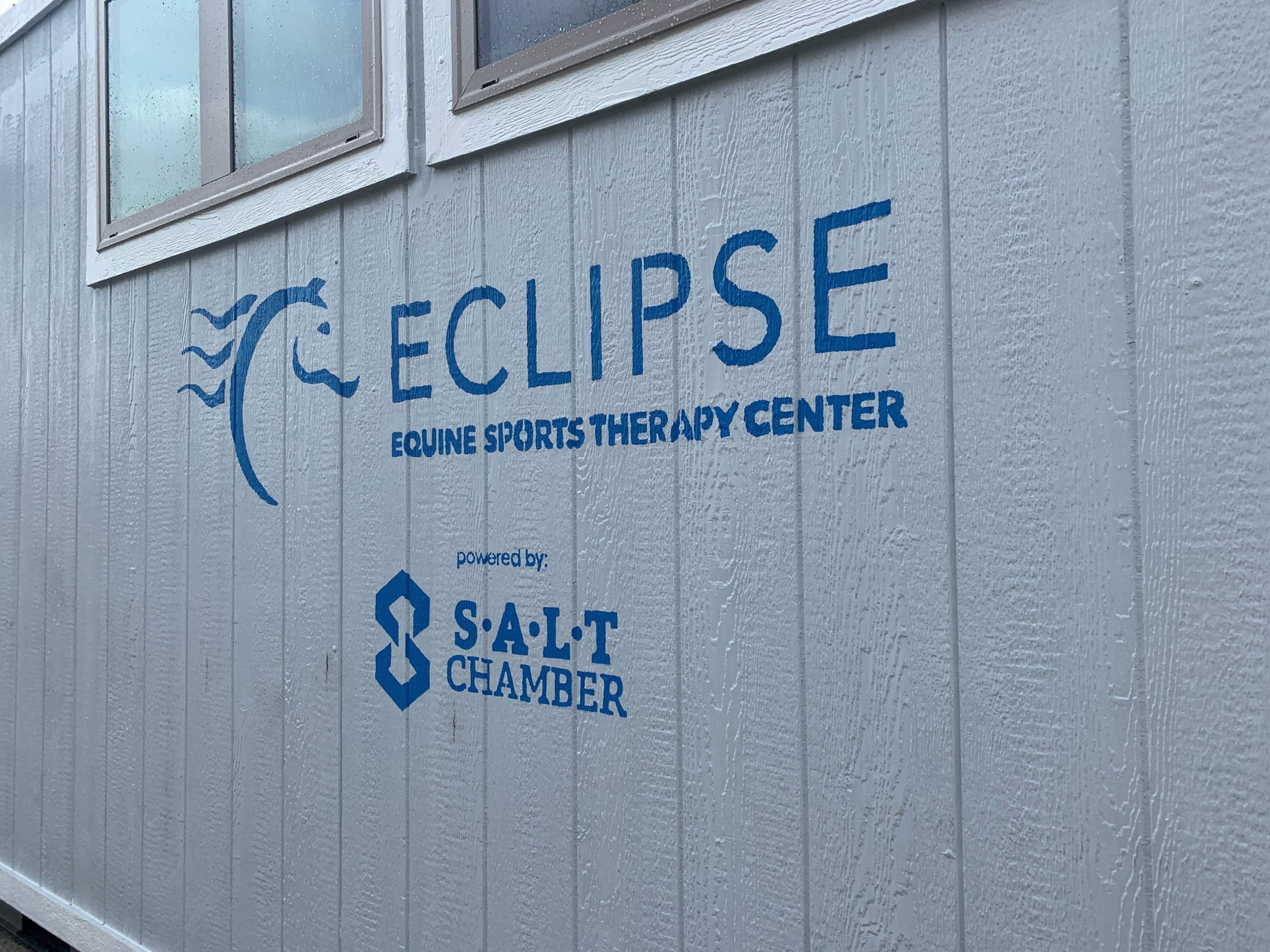 An Outer View Of The Wall At Eclipse Equine Sports Therapy Center, With A Sign That Reads Eclipse Equine Sports Therapy Center Powered By Salt Chamber