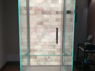 Salt Booth With A White Backlit Salt Wall With A Stand To The Right At Energy Spa And Tanning.