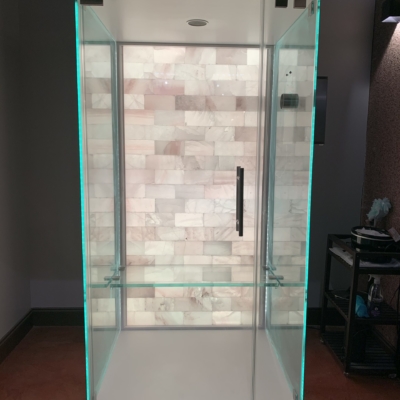 Salt booth with a white backlit salt wall with a stand to the right at Energy Spa and Tanning.