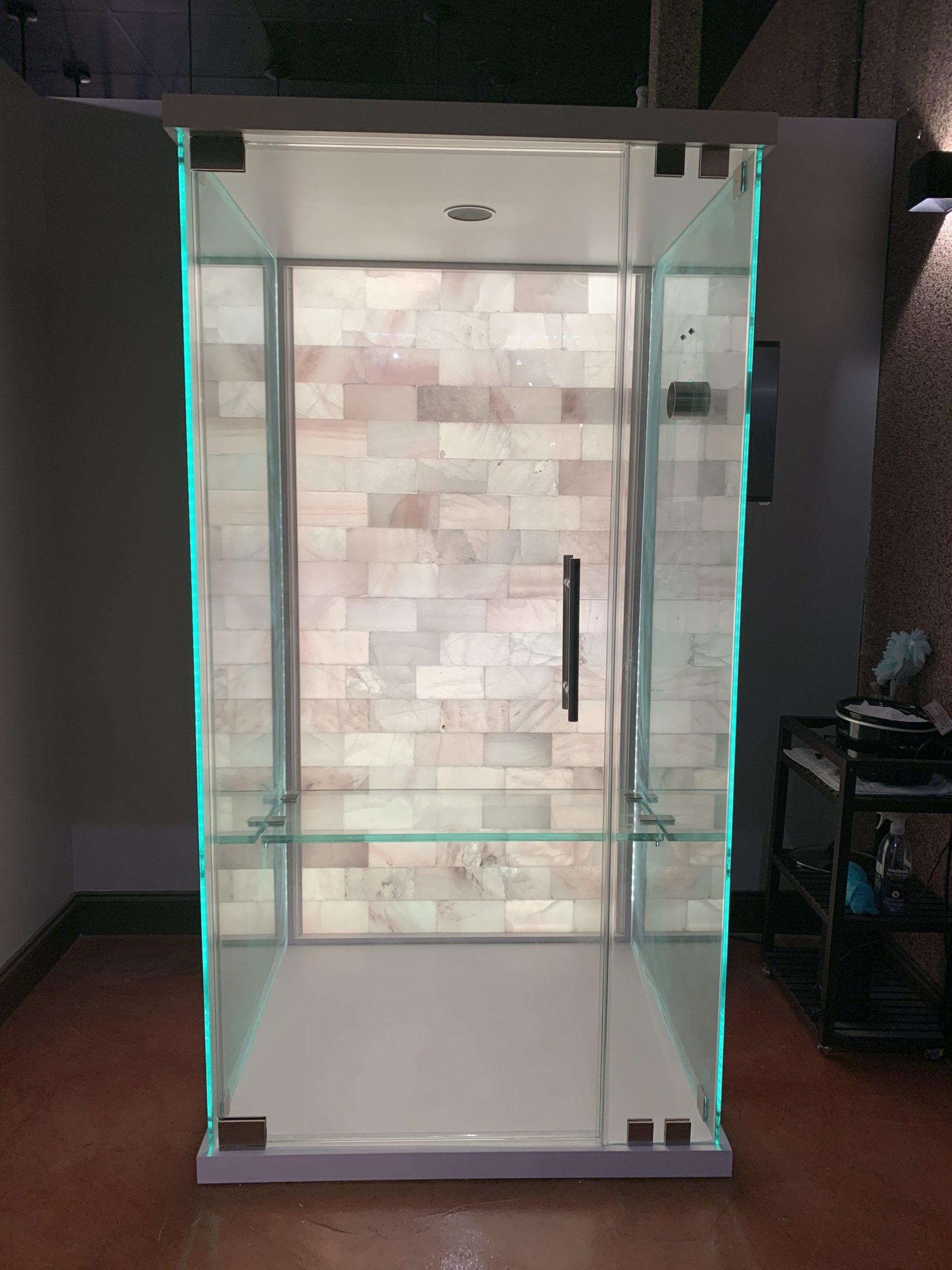 Salt booth with a white backlit salt wall with a stand to the right at Energy Spa and Tanning.