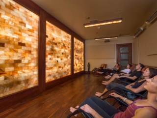 Two Men And Four Women Relaxing In Lounge Chairs Facing A Led Backlit Salt Stone Wall.