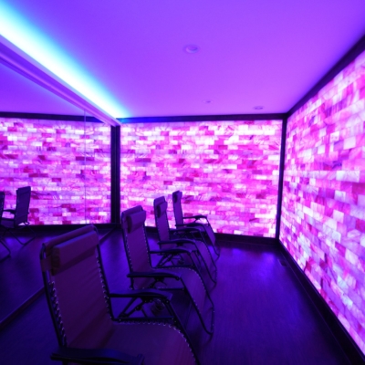 Four Reclining Chairs In Front Of A Mirror With A Purple Led Backlit Salt Panel Wall At Float Into Wellness And The Salt Lounge &Amp; Sauna Spa - Woodbridge, Nj.