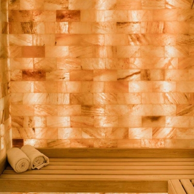 A Light Wooden Corner Booth With Two Towels And A Backlit Orange Himalayan Salt Brick Wall At The Henderson Beach Resort.