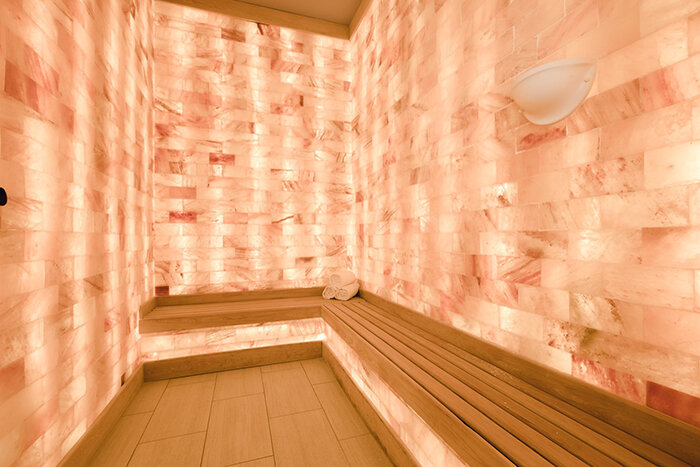 LED backlit Himalayan salt panel wall with a light brown bench and three towels stacked up in the corner at the Henderson Beach Resort - Destin, Florida.
