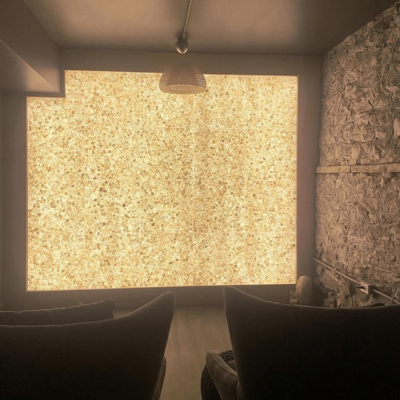 Two Black Chairs In A Dark Room With A Himalayan Salt Stone Wall Backlit With Orange Lighting.