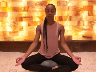 Woman Meditating On A Salt-Covered Floor In Front Of A Led Backlit Salt Panel Wall At The Intown Salt Room - Atlanta, Georgia.