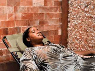 Women Relaxing In A Reclined Chair In A Salt Room With A Himalayan Salt Paneled Wall And A Himalayan Salt Stone Wall At The Intown Salt Room.