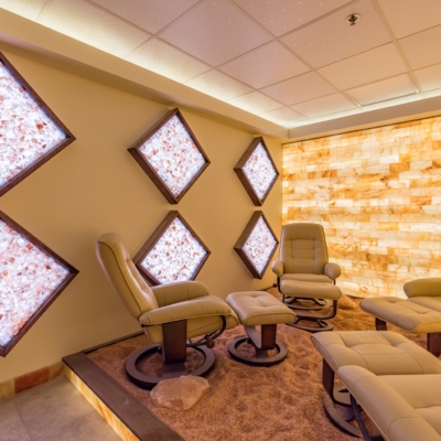 Four White Chairs All With White Foot Rests On A Bed Of Himalayan Salt With Six White Led Back Lit Diamond Salt Panel Décor And A Led Back Lit Salt Brick Wall At The Kalahari Resort.