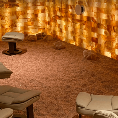 Four cushioned lounge chairs on a salt-covered floor with seven large Himalayan salt bricks and an LED backlit salt panel wall.