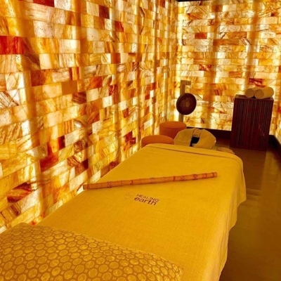 A Massage Table At The Kudadoo Salt Room Surrounded By Orange Backlit Salt Stone Paneled Walls.