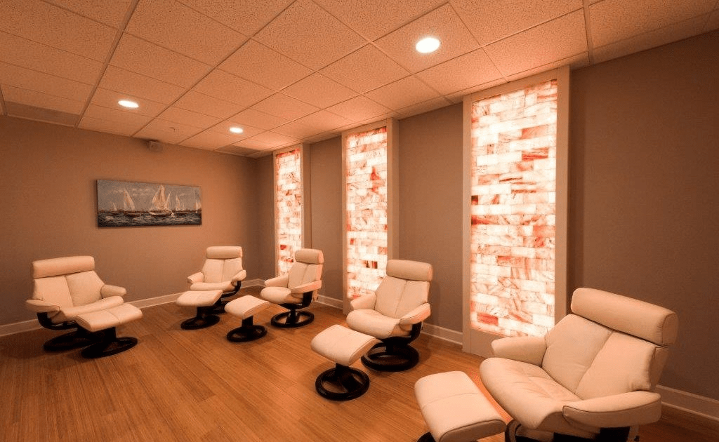 5 Cushioned Chairs In A Room With 3 Pink Salt Bricks Walls In Laurel Parc Senior Living Community'S Salt Room