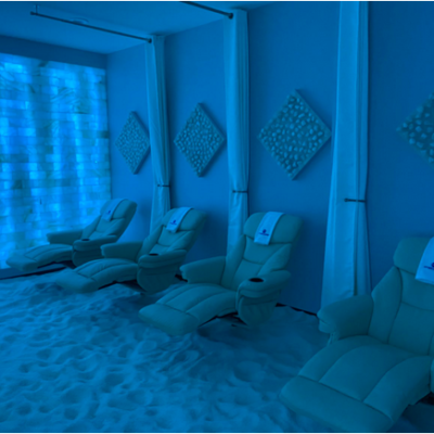 Four Cushioned Lounge Chairs, Four Diamond Salt Stone Décor Above Them, And A Salt Stone Wall With Blue Back Light.