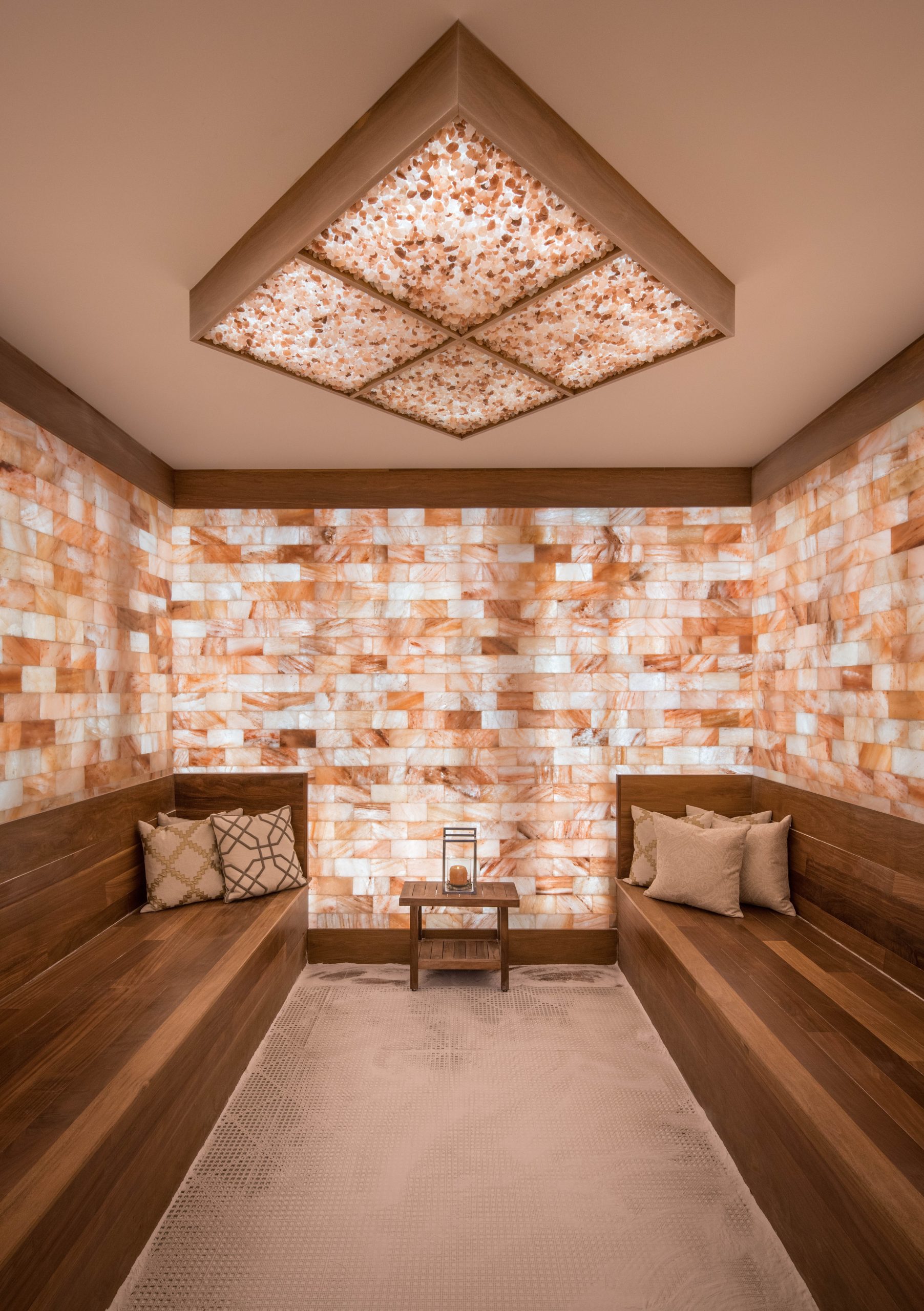 Two Wooden Booths With Three Pillow Son Each Surrounded By Led Backlit Salt Panels With A Diamond Salt Brick Ceiling Fixture At Palm Health - Ladue, Missouri.