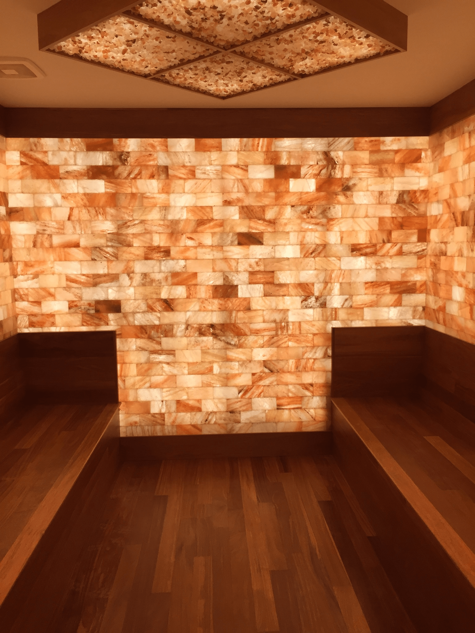 Two Wooden Booths Surrounded By Led Backlit Salt Panels And A Slat Brick Ceiling Fixture At Palm Health - Ladue, Missouri.