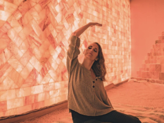 Woman Stretching On A Blanket On A Salt-Covered Floor In Front Of A Led Backlit Salt Panel At The Prana Salt Cave &Amp; Yoga - Wilmington, Nc.