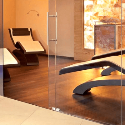 Four White And Black Chaises On A Dark Wooden Floor Through A Glass Door With An Orange Backlit Himalayan Salt Stone Wall At A Private Residence.