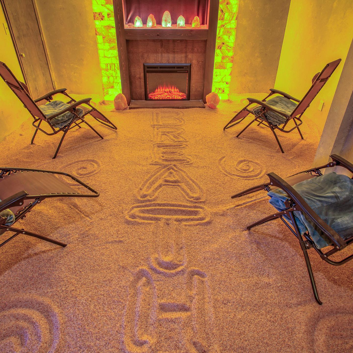 Four Reclining Chairs On A Salt Covered Floor With Writing That Says &Quot;Breath&Quot; Facing A Fireplace With Led Backlit Salt Panels At The Radiant Well-Being - Boone, North Carolina.